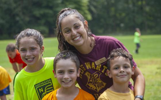 three kids with a camp counselor smiling at the camera