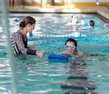 ymca instructor works with member during swim lesson